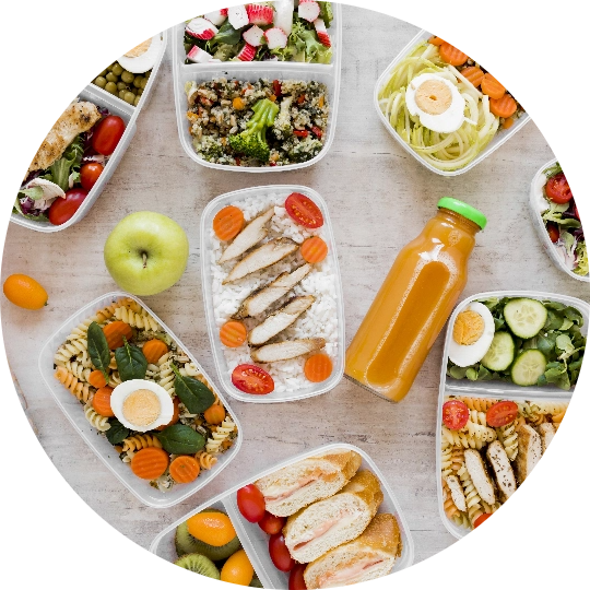 An apple, orange juice, and plastic containers of meals scattered on a table.