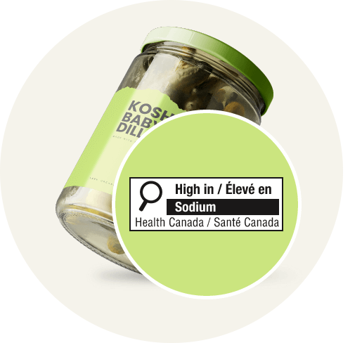 Glass jar of kosher baby dill pickles featuring a Health Canada front-of-pack label warning in a green circle for high sodium content.