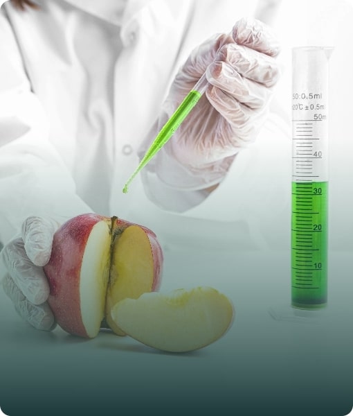 A hand in a lab coat performing an experiment with a green liquid and an apple, symbolizing food science research.